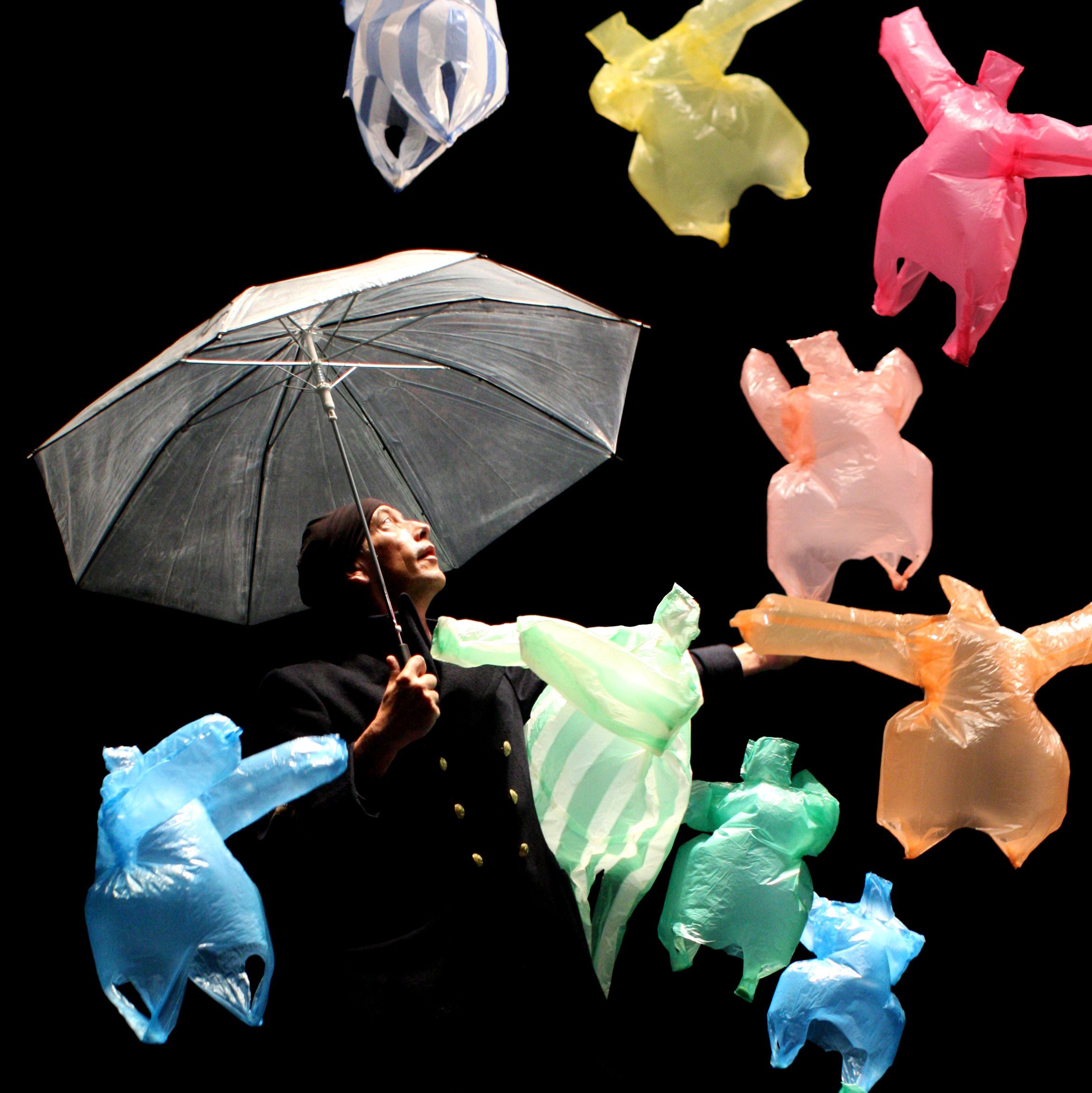 Eine Person mit Regenschirm, umgeben von fliegenden Plastikfiguren