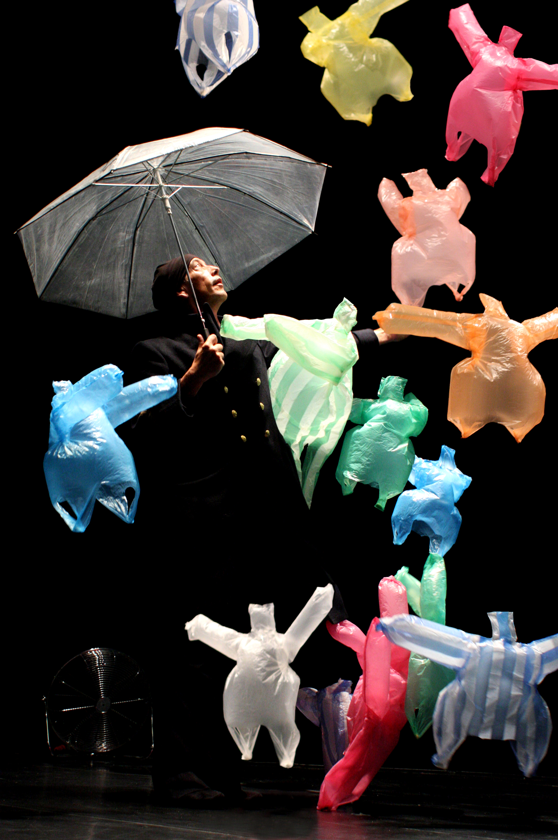Eine Person mit Regenschirm, umgeben von fliegenden Plastikfiguren